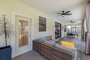A sunlit patio with a wicker sofa, ceiling fans, and a view of the outdoors. - ChampionsGate Resort Perks! Fun-Filled Family Home (Davenport)