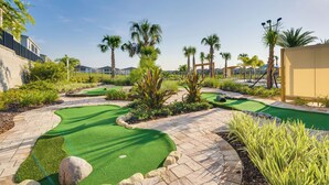 A miniature golf course with green artificial turf, palm trees, and stone pathways. - ChampionsGate Resort Perks! Fun-Filled Family Home (Davenport)