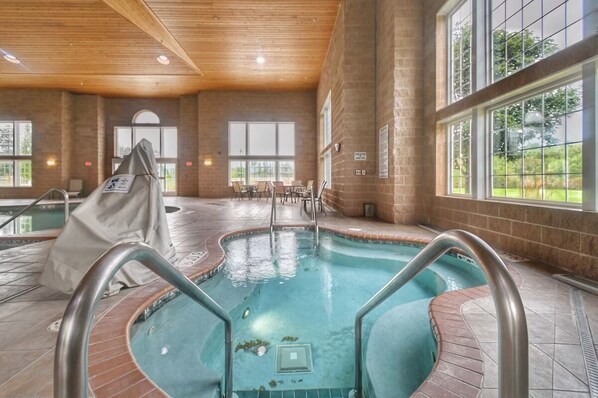 An indoor swimming pool with clear water, surrounded by brick walls and large windows. - Romantic Riverside Escape | Pool, Spa & Golf at The Four Seasons Island Resort! (Pembine)