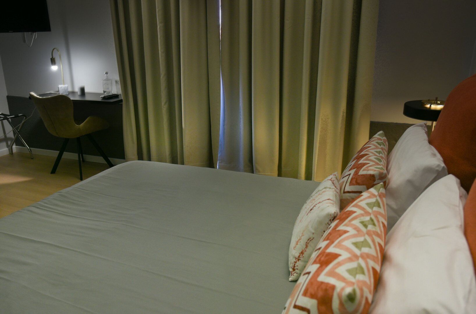 A hotel room with a bed, a desk, a chair, and curtains.