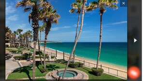 A resort with a pool, palm trees, and a beach view. - Ocean front with new,updated interior.  Oversized balcony with BBQ. Perfect!! (Cabo San Lucas)