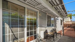 Une terrasse couverte avec de grandes portes-fenêtres coulissantes, une terrasse en briques et du mobilier d’extérieur.