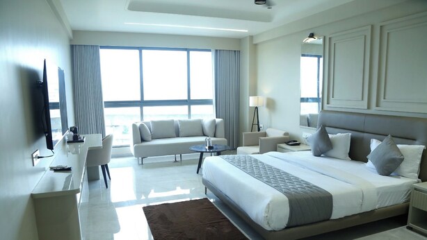 Una habitación de hotel moderna con una cama grande, un sofá, un escritorio y un televisor.