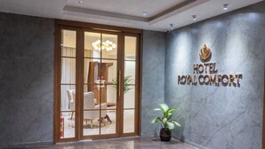 Un hall de hotel con piso de mármol, una recepción y un cartel que dice "HOTEL ROYAL COMFORT".