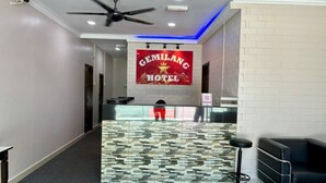 A hotel reception area with a modern design, featuring a patterned counter, a ceiling fan, and a prominent hotel sign. - Gemilang Star Hotel (Port Dickson)