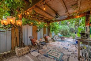Un patio exterior con vigas de madera rústica, asientos acolchados y un suelo estampado.