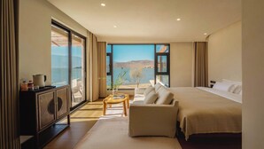 A modern hotel room with a large bed, a sofa, a wooden coffee table, and a view of the sea through large windows. - Dali Antu Yuanchu seaview Homestay (Dali)