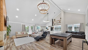 A spacious living area with a wooden floor, a dining table, a sofa, and a lounge chair. - Upscale Retreat-Games, Comfort & Cozy Vibes Await! (Houston)