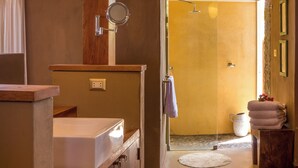 Un baño con tocador de madera, un espejo y zona de ducha.