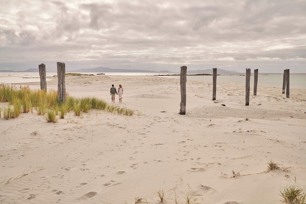 Une plage de sable avec des poteaux en bois et des empreintes de pas.