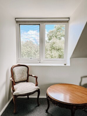 Ein Zimmer mit Fenster, einem Stuhl und einem Tisch.