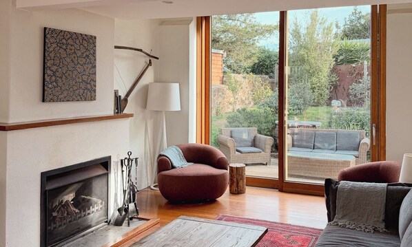 A living room with a fireplace, a large window, and a view of the outdoors.