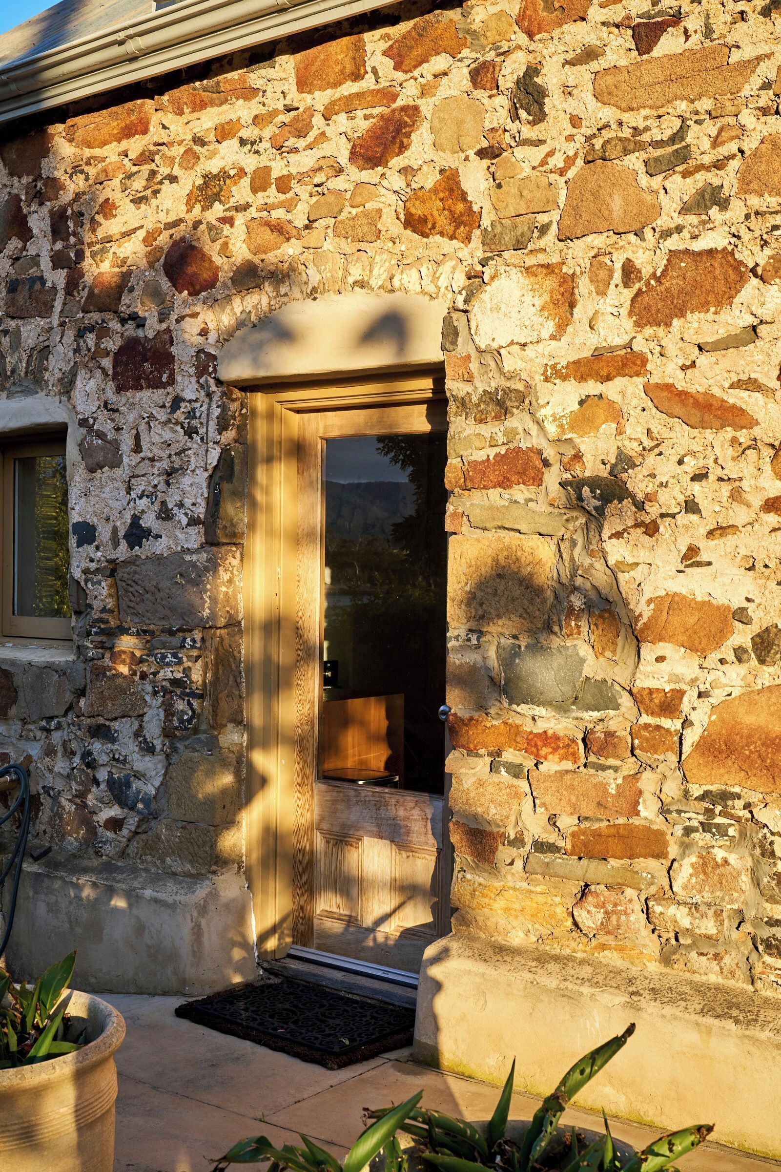 A stone building with a wooden door and a small porch area.