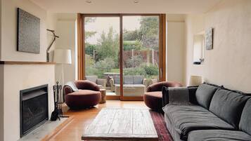 A living room with a fireplace, a large sliding glass door to a garden, and a sofa.