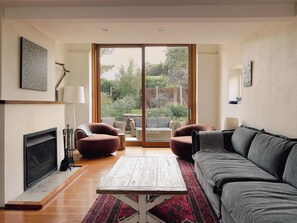 Ein Wohnzimmer mit Kamin, einer großen Schiebetür zum Garten und einem Sofa.