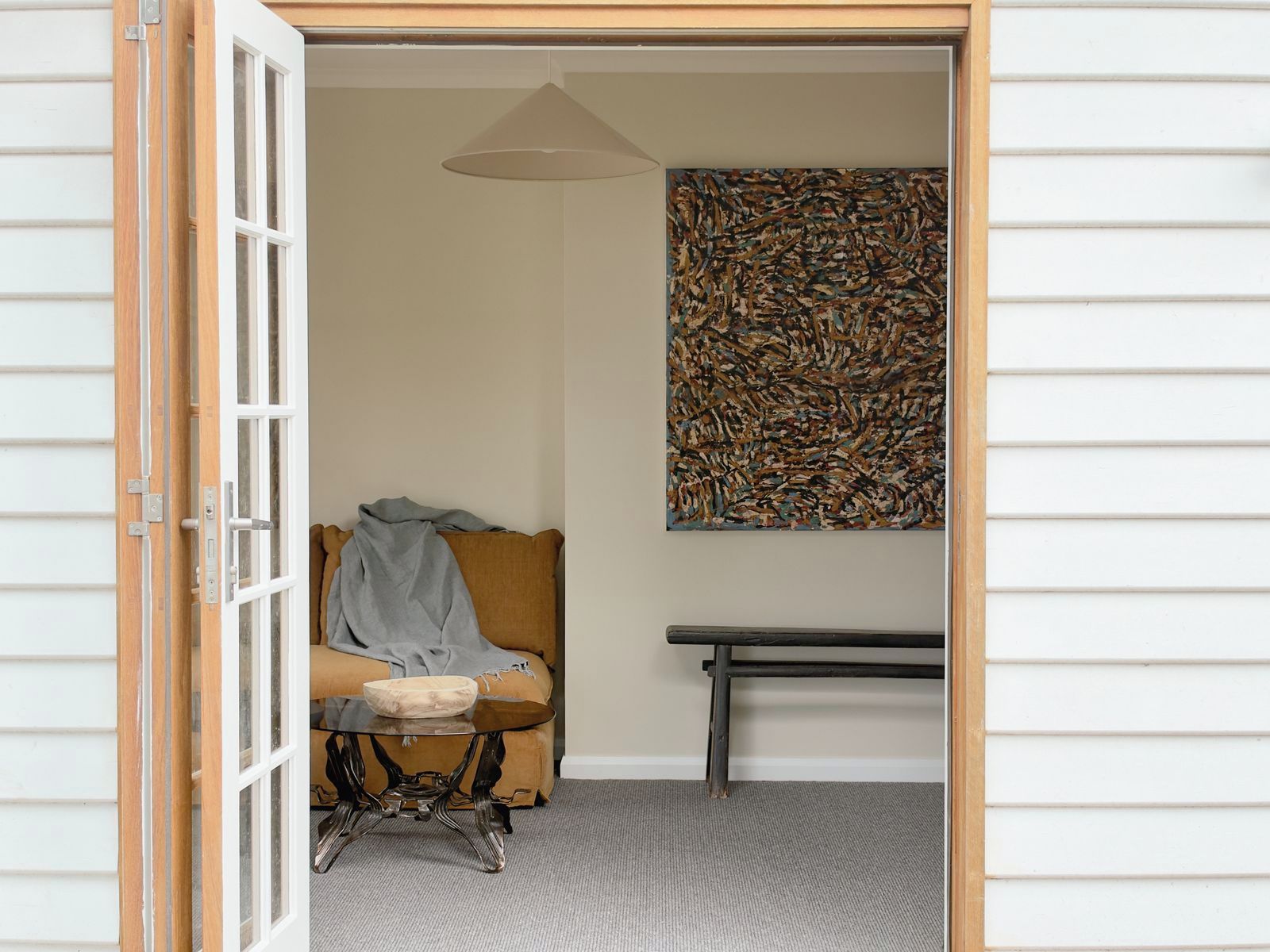 A room with a sofa, a table, and a wall-mounted abstract painting.
