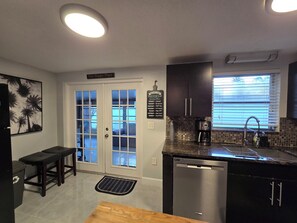 A kitchen with a dishwasher, a coffee maker, and a window with blinds.