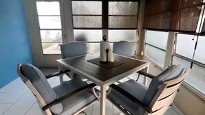 Ein Zimmer mit einem runden Tisch und sechs Stühlen, großen Fenstern mit Jalousien und einer blauen Wand.