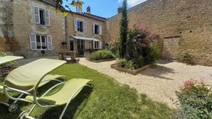 Un cortile con un prato, un muro in pietra e un edificio con tetto in tegole.