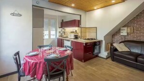 Un ambiente compatto con zona pranzo, angolo cottura e soggiorno dotato di divano.