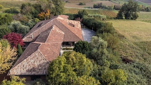 Una villa con diversi tetti, immersa nel verde e circondata da vigneti.