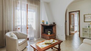 Un salon comprenant un canapé, une table basse, une cheminée et une porte donnant sur une autre pièce.