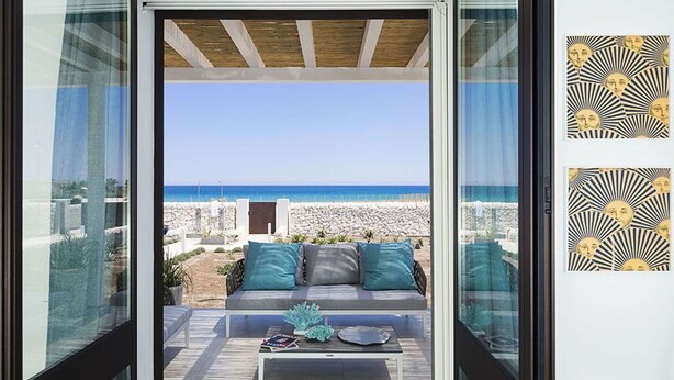 A modern living room with a view of the beach, a sofa with cushions, a coffee table, and a patterned wall. - Wonderful private villa for 6 people with WIFI, A/C, private pool, TV, terrace and panoramic view (Reitani)
