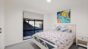 Une chambre à coucher avec un lit, une fenêtre donnant sur un beau paysage, une table de chevet et un tableau accroché au mur.