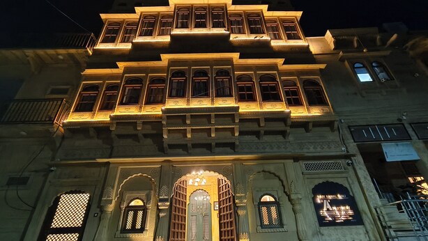 A multi-story building with ornate architectural details, including arched windows and decorative elements around the entrance. - Svarn By Experience Jaisalmer (Jaisalmer)