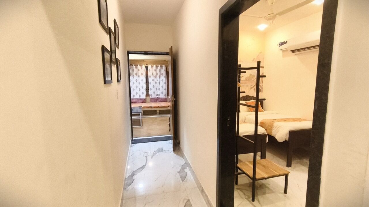 A narrow hallway with a bed and a wooden chair in a room.