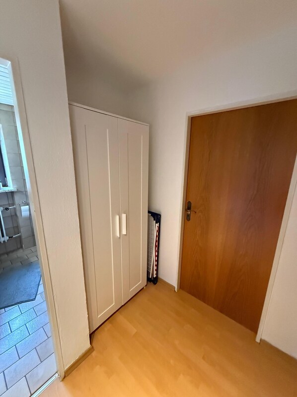 A room with a wooden floor, a white wardrobe, and a wooden door.