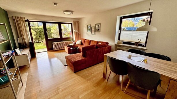 Una sala de estar moderna con un sofá, una mesa de comedor con sillas, un radiador y una ventana con vistas al exterior.