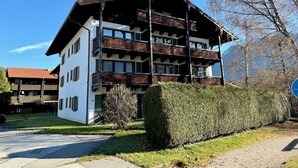 Un edificio de varios pisos con balcones, fachada blanca y tejado rojo.
