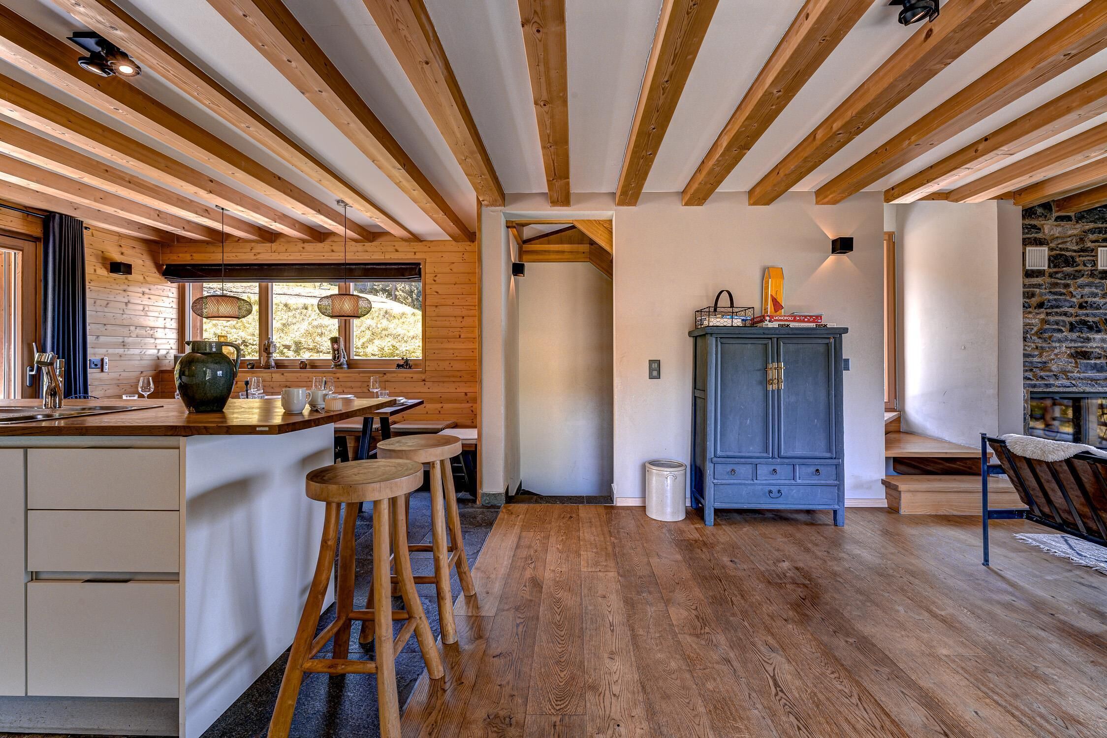 A kitchen with wooden beams, a stone wall, and a blue cabinet.