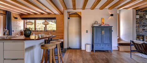 A kitchen with wooden beams, a stone wall, and a blue cabinet.