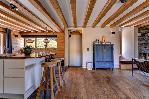 A kitchen with wooden beams, a stone wall, and a blue cabinet.