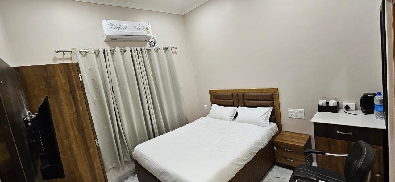 Une chambre d’hôtel équipée d’un lit, d’un bureau, d’une chaise, d’une armoire et d’un appareil de climatisation.
