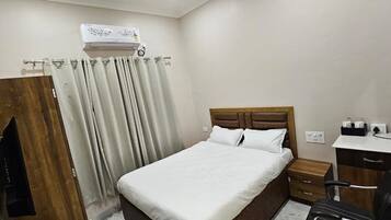 Une chambre d’hôtel équipée d’un lit, d’un bureau, d’une chaise, d’une armoire et d’un appareil de climatisation.