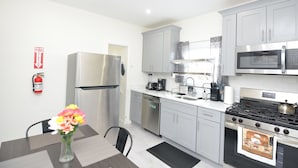 A modern kitchen with grey cabinets, stainless steel appliances, and a dining area with a table and chairs.