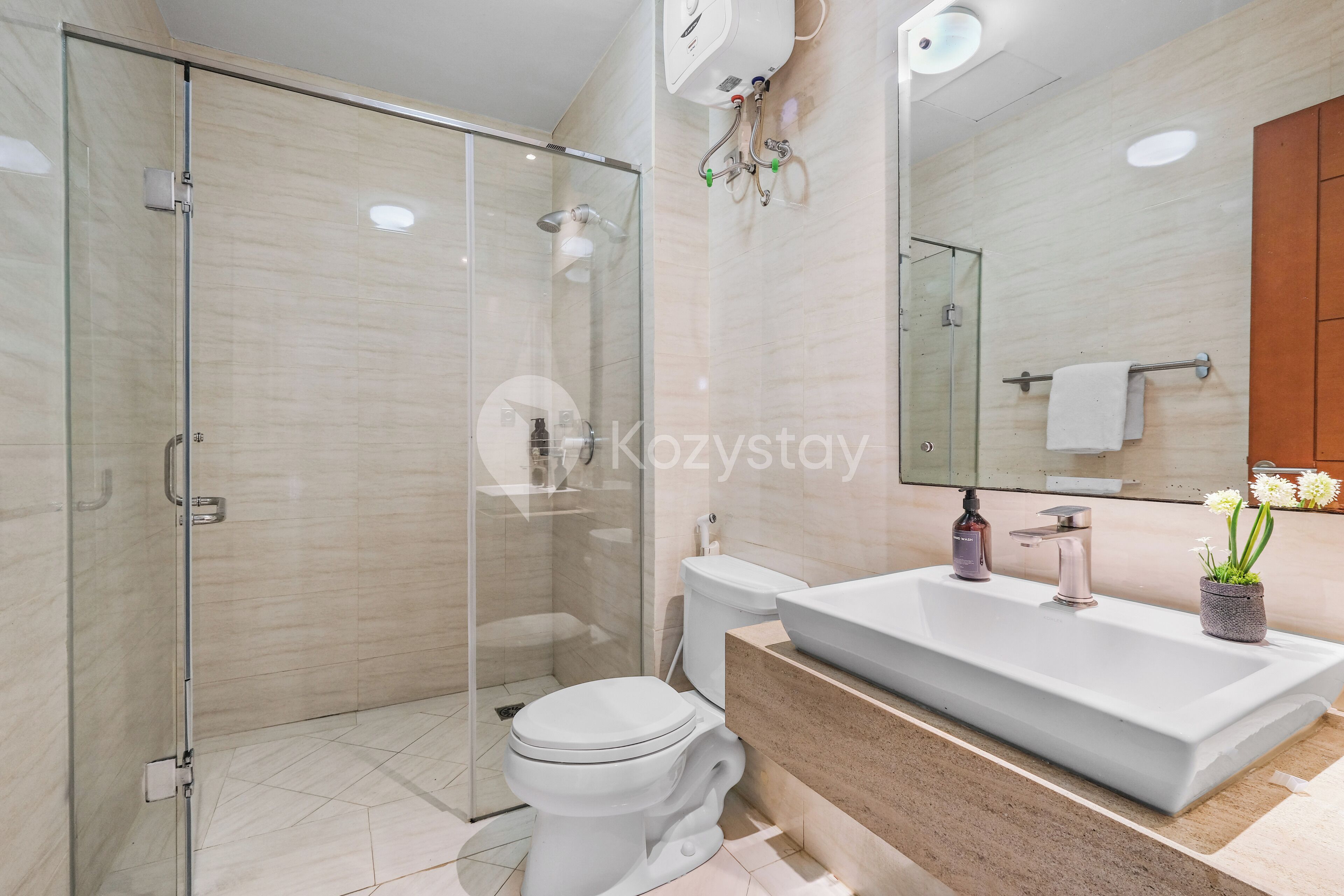A modern bathroom with a glass shower enclosure, a white toilet, and a large sink with a mirror above.