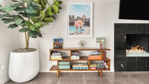 Un salon avec une grande plante en pot, une bibliothèque, un tableau encadré représentant une girafe et une cheminée.