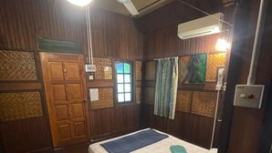 Een kamer met een bed, houten wanden, een raam en een airconditioning.
