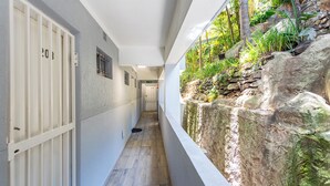 Un couloir étroit, avec un mur de pierre d’un côté et une porte blanche de l’autre.