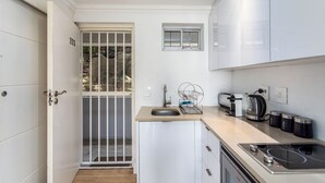 Une petite cuisine équipée d’un évier, d’un grille-pain, d’une bouilloire et d’une cuisinière.