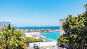 Une vue sur la côte, avec une plage, des voitures et un bâtiment doté d’un balcon donnant sur la mer.