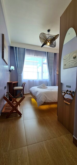 Una habitación de hotel con cama, una silla, un escritorio y un espejo.