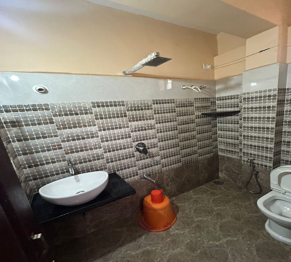 Um banheiro com parede de chuveiro revestida em azulejo, pia e vaso sanitário.
