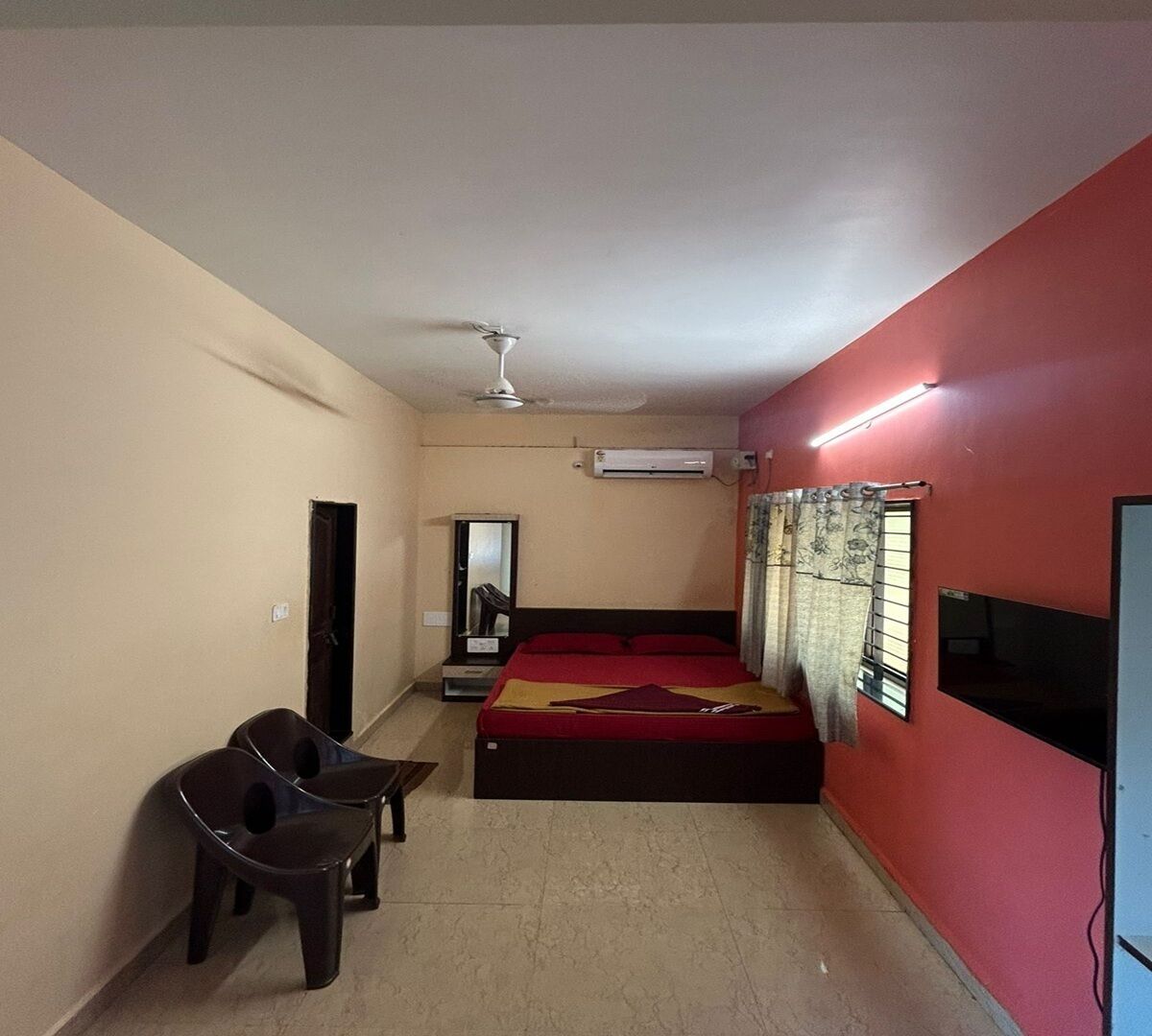 A bedroom with a bed, a chair, a wardrobe, an air conditioner, and a ceiling fan.