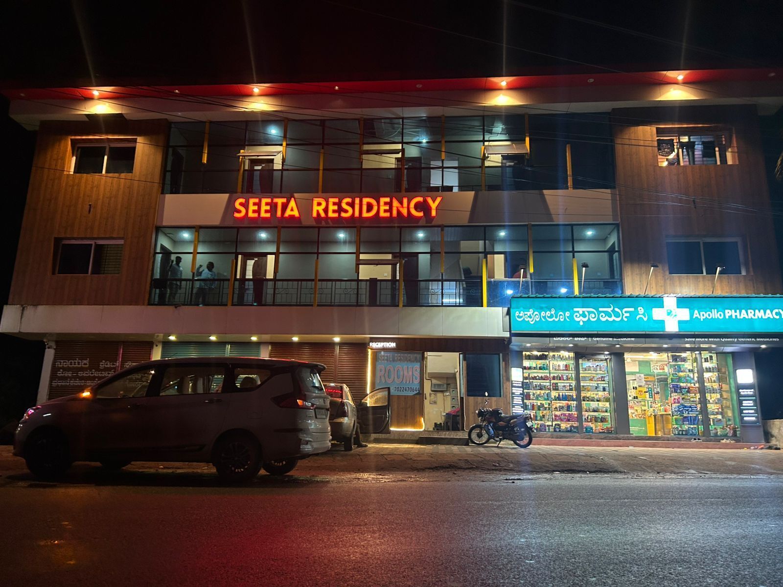 Un edificio de dos pisos con un cartel que dice 'SEETA RESIDENCY' y una farmacia llamada 'Apollo PHARMACY'.