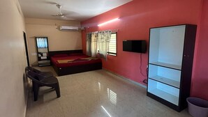 A room with a bed, a desk, a chair, a TV, and a wardrobe. - Seeta Residency (Gokarna)